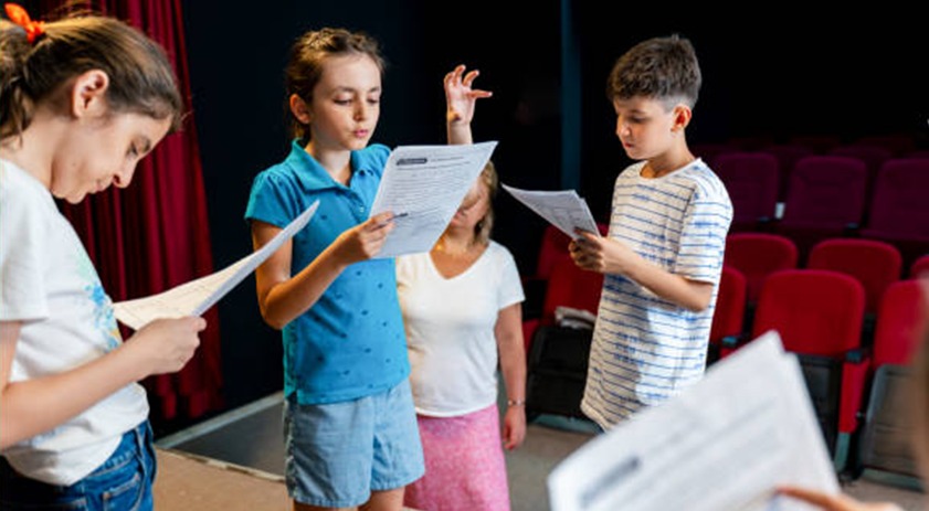 Students rehearsing scripts together on a theatre stage as part of LAMDA exam preparation